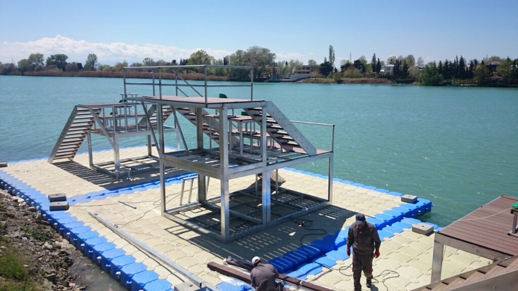 Floating metal platform with dual stair and railing structures on the waterfront
