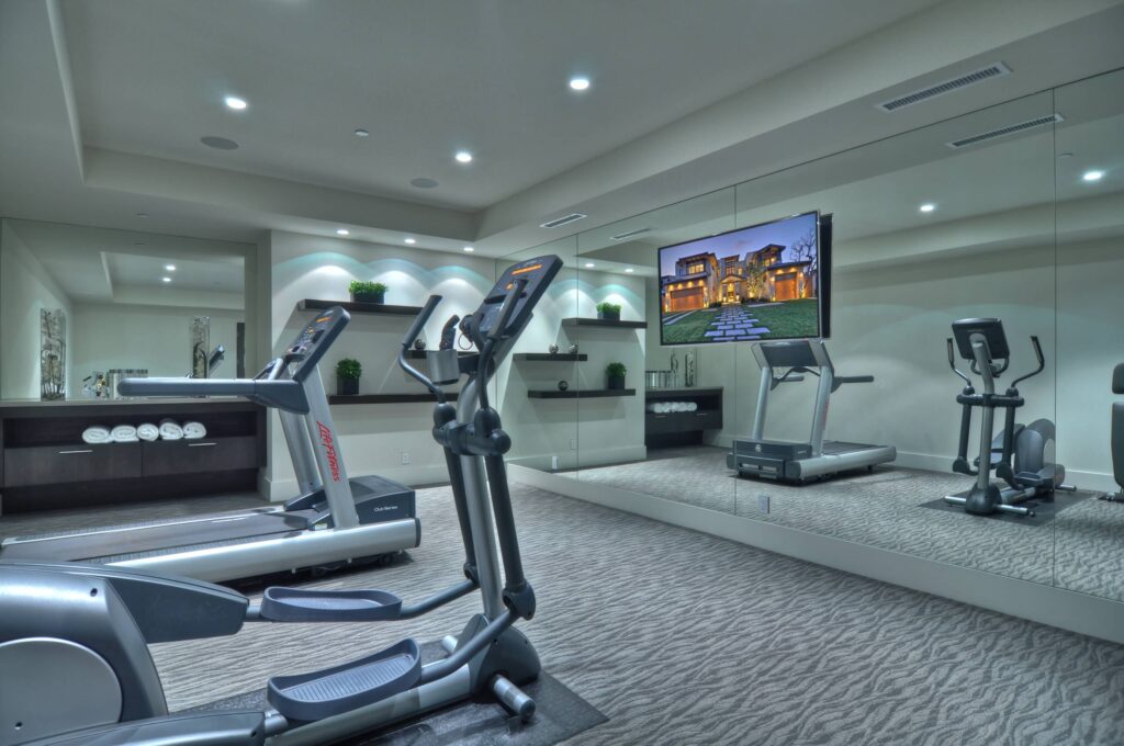 Basement gym with mirrored walls and rubber flooring.