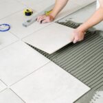 person laying ceramic tiles